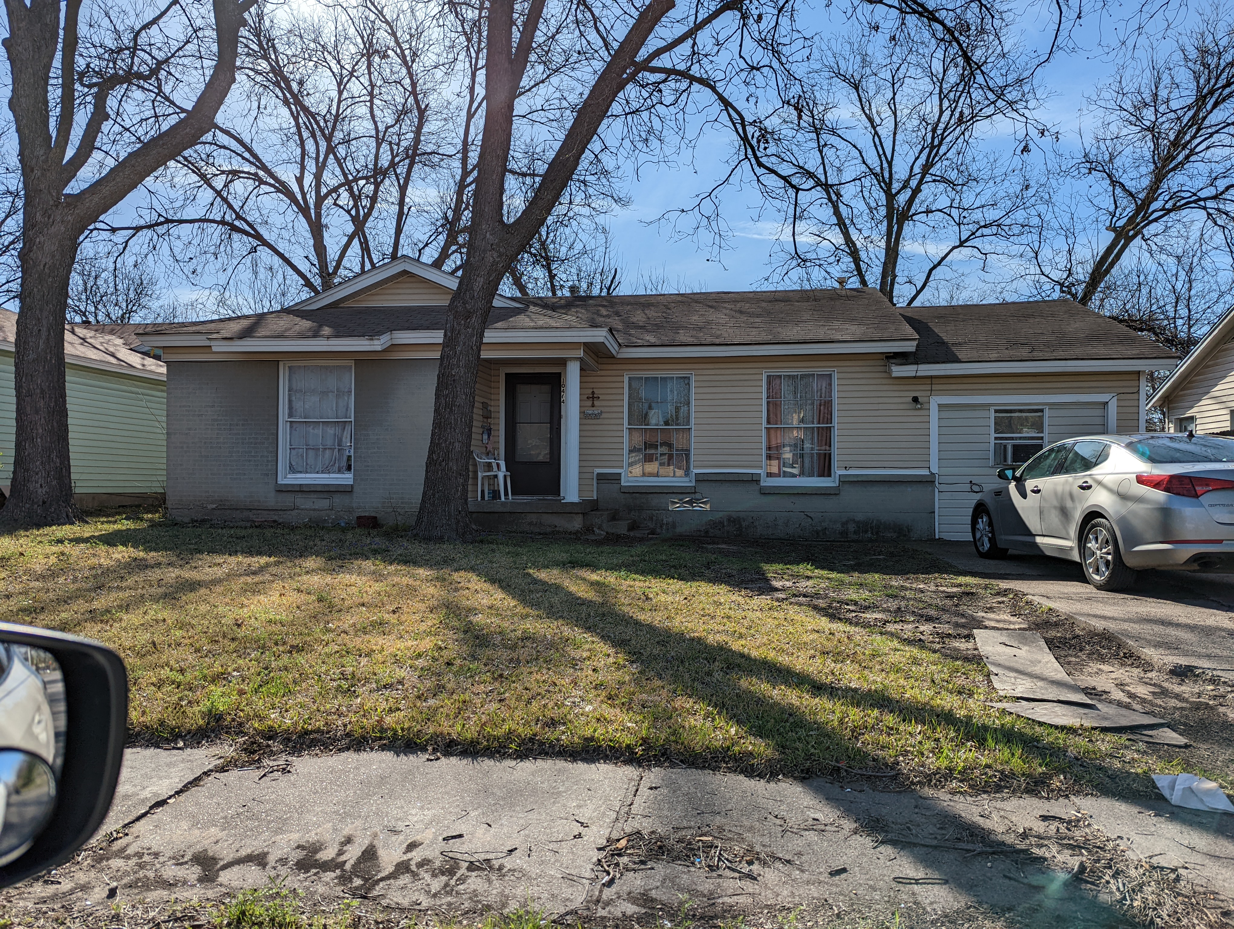 A small home with tall trees and a grass lawn.