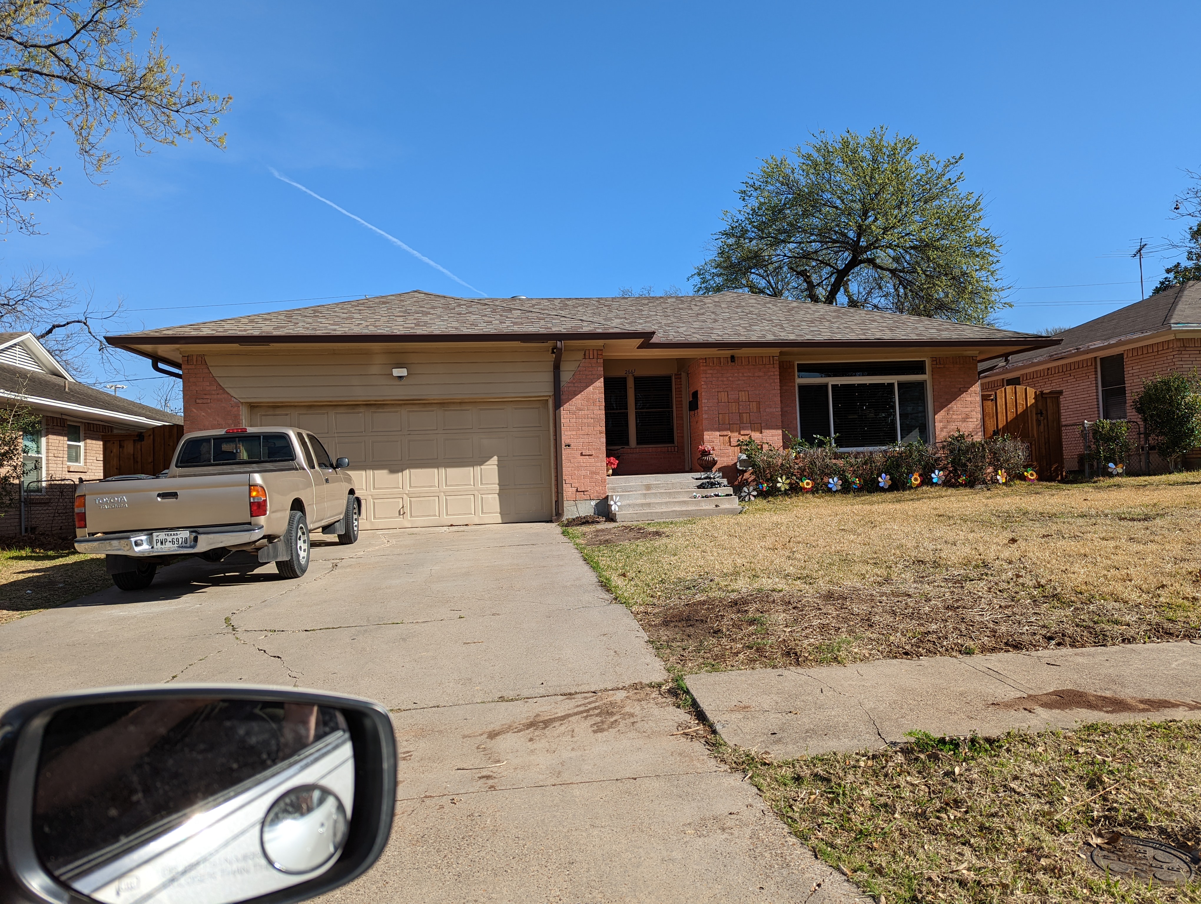 A small brick home with a small truck in the driveway and a lawn.